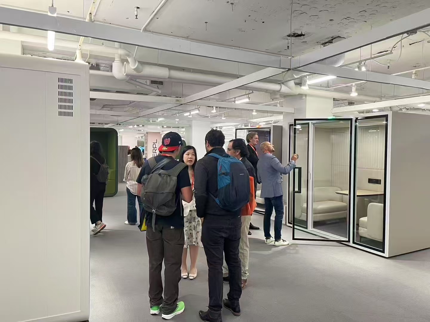 soundbox-team-visitors-acoustic-pods-neocon-2025.jpg Soundbox team discussing custom acoustic pods with visitors at NeoCon 2025