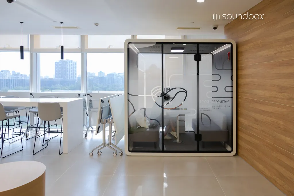 Bright modern office with a person working inside a Soundbox SR acoustic pod.