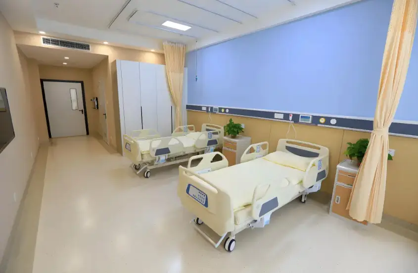 Hospital patient room with two adjustable beds and privacy curtains