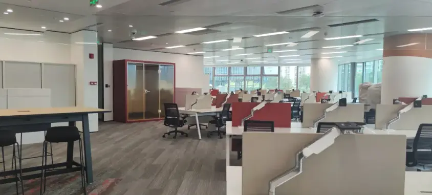 Open-plan workplace with individual workstations and an enclosed acoustic pod